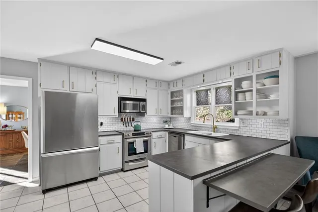 a kitchen with stainless steel appliances granite countertop a stove a refrigerator a sink a stove with white cabinets and wooden floor