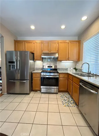 a kitchen with granite countertop a stove a sink and a refrigerator