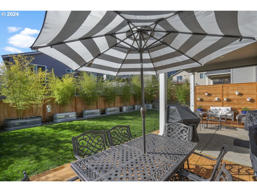 59551 Emerald Loop St. Helens, OR 97051 - Photo 15 of 40 a view of a patio with table and chairs under an umbrella with a small yard