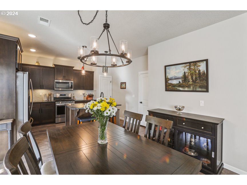 59551 Emerald Loop St. Helens, OR 97051 - Photo 19 of 40 a kitchen with stainless steel appliances a dining table chairs refrigerator and microwave