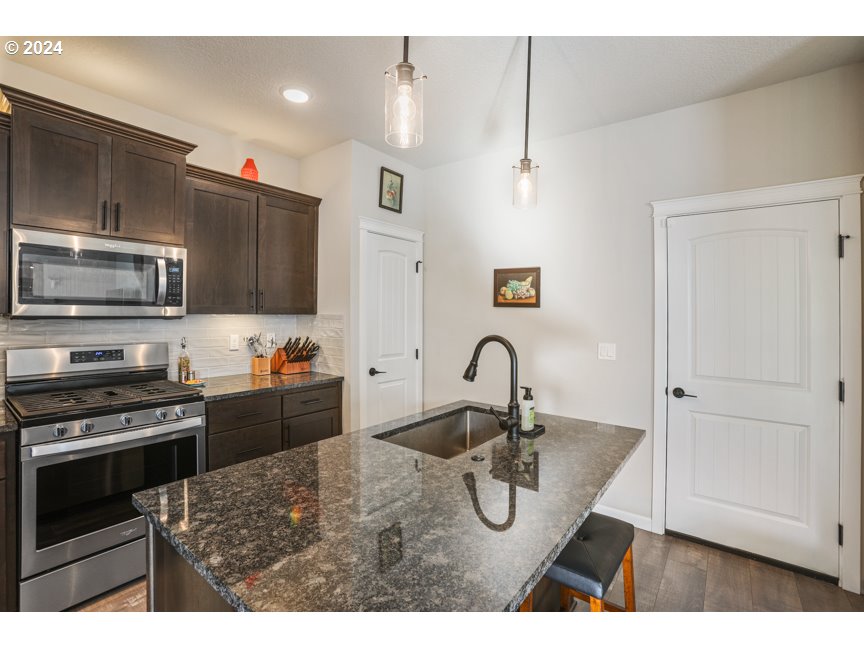 59551 Emerald Loop St. Helens, OR 97051 - Photo 20 of 40 a kitchen with kitchen island a stove a sink and a microwave