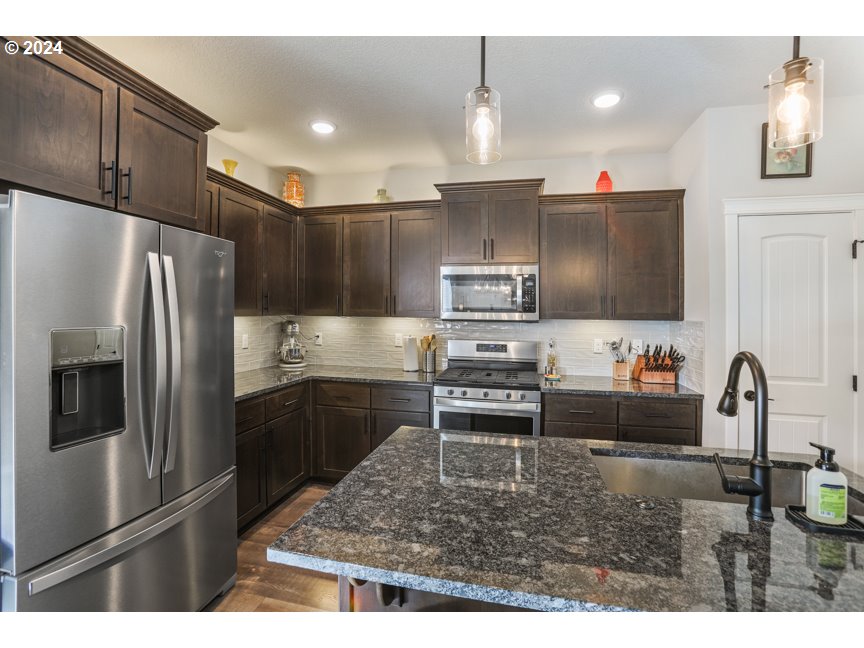 59551 Emerald Loop St. Helens, OR 97051 - Photo 21 of 40 a kitchen with stainless steel appliances kitchen island granite countertop a refrigerator and a stove top oven