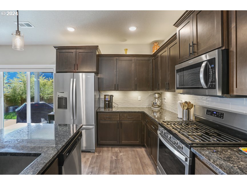 59551 Emerald Loop St. Helens, OR 97051 - Photo 22 of 40 a kitchen with granite countertop stainless steel appliances and wooden cabinets
