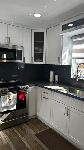 a kitchen with kitchen island granite countertop a sink stainless steel appliances and cabinets