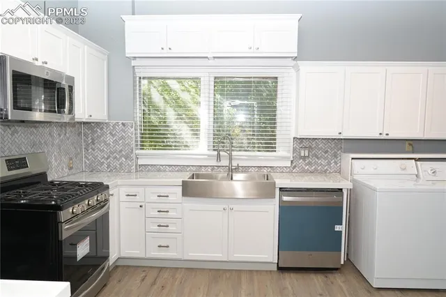 a kitchen with cabinets appliances a sink and a window