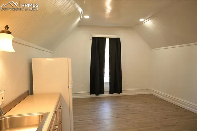 an empty room with wooden floor and entrance