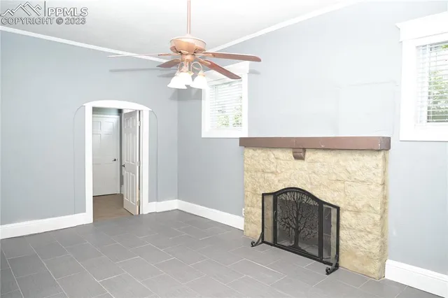 a view of an empty room with chandelier fan and fire place