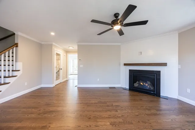 a view of an empty room with wooden floor and a fireplace