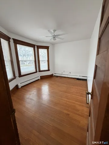 an empty room with wooden floor fan and windows
