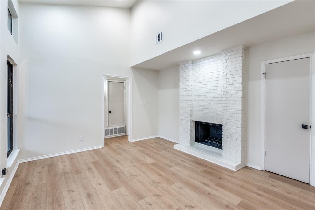 17490 Meandering Way, Unit 2202 Dallas, TX 75252 - Photo 5 of 24 Spacious living area featuring high vaulted ceilings, light wood-finish flooring, a white-painted brick fireplace, recessed lighting, and large windows