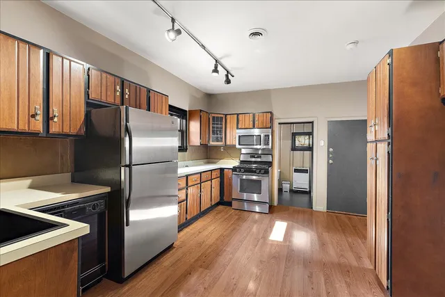 a kitchen with stainless steel appliances wooden floor sink and refrigerator
