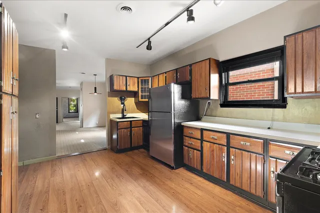 a kitchen with stainless steel appliances granite countertop a refrigerator a sink dishwasher a stove and white countertops with wooden floor