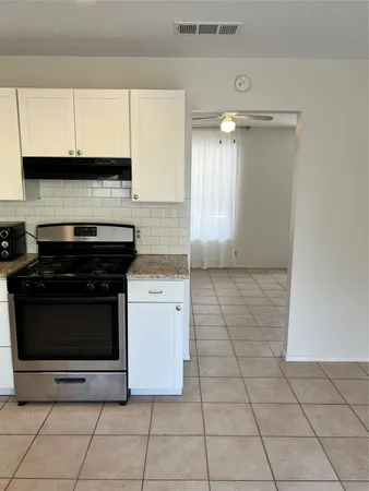 a kitchen with granite countertop a stove a sink and a microwave