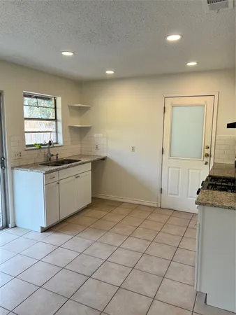 a kitchen with a sink a stove cabinets and a window