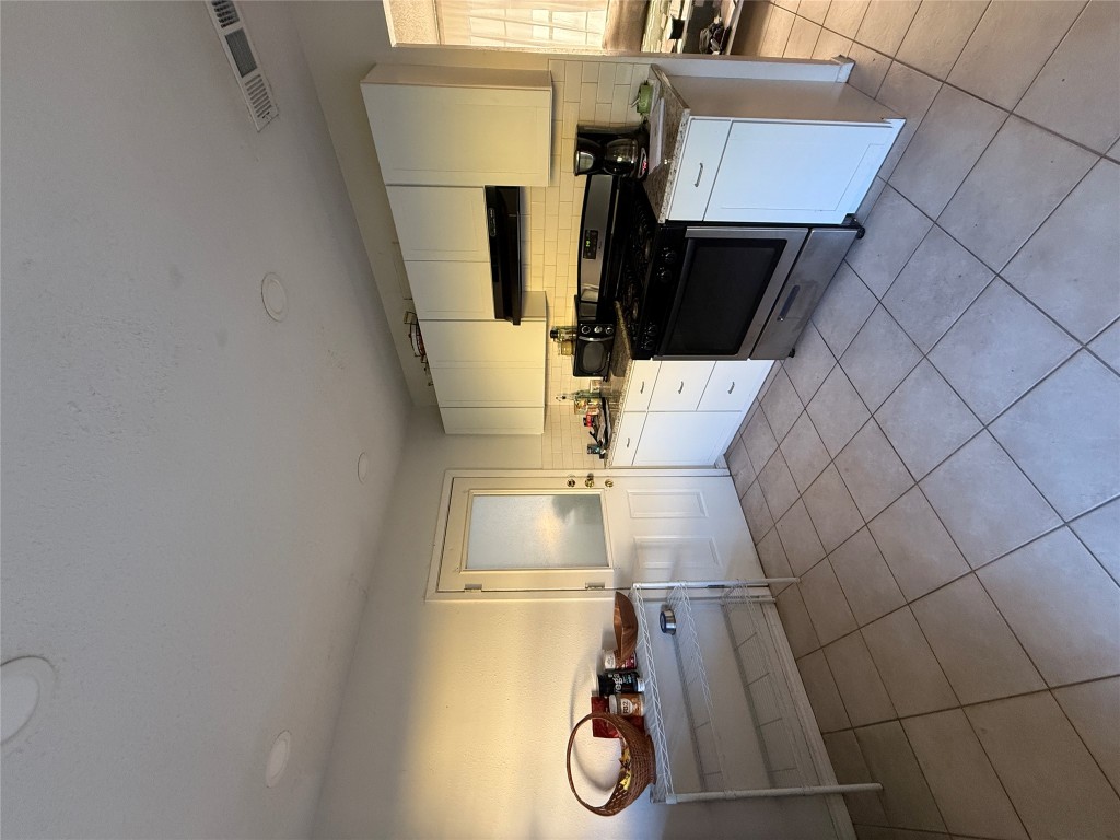 8311 Hathaway Drive, Unit A Austin, TX 78757 - Photo 4 of 6 a kitchen with stainless steel appliances kitchen island granite countertop a sink and white cabinets