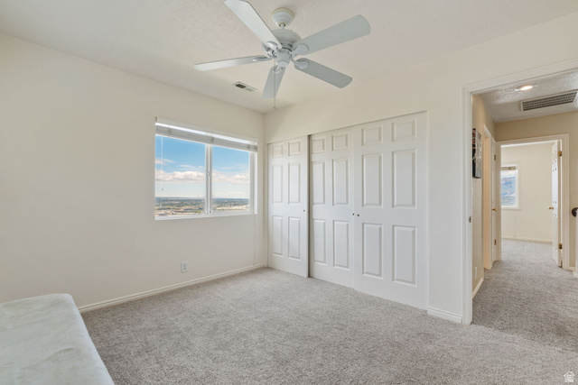 14883 Tooele Lane Draper, UT 84020 - Photo 32 of 49 Bright room featuring a ceiling fan, light gray carpeting, and a large window with a distant landscape visible