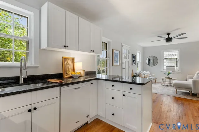 a kitchen with granite countertop white cabinets white appliances with a sink and wooden floor