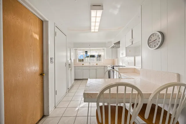 a view of a kitchen with kitchen island stainless steel appliances refrigerator stove and a window