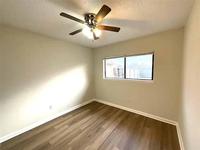 a view of empty room with wooden floor and fan