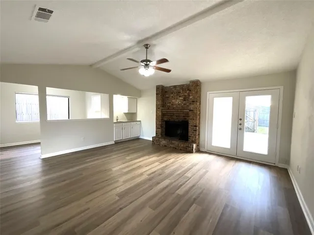 an empty room with wooden floor fireplace and windows