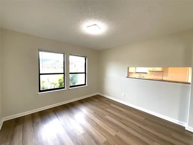 a view of an empty room with window and wooden floor