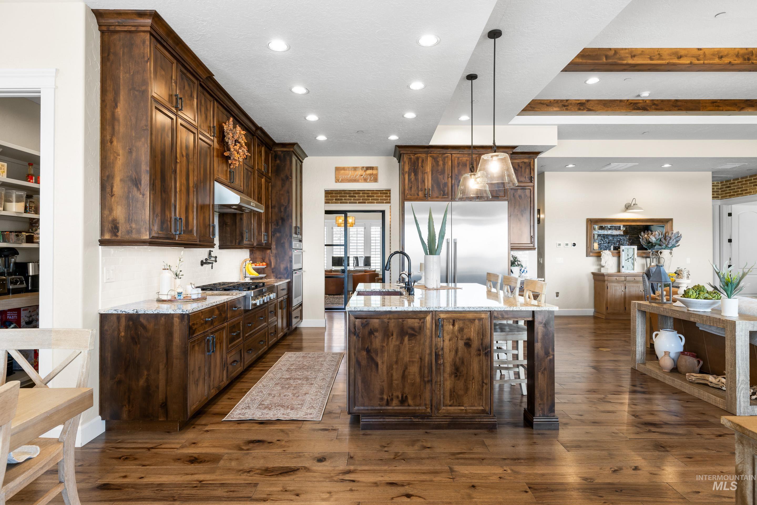 9819 Foothill Road Middleton, ID 83644 - Photo 22 of 49 Kitchen featuring dark wood-type flooring, recessed lighting, an island with sink, dark brown cabinets, and light stone counters
