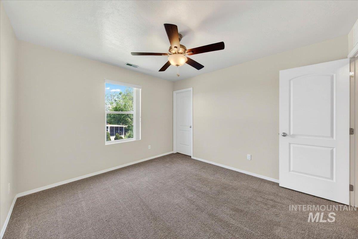 1555 Condor Drive Middleton, ID 83644 - Photo 38 of 50 Spacious room featuring neutral paint tones, plush carpeting, a multi-pane window, a ceiling fan with integrated lighting, and a paneled interior door