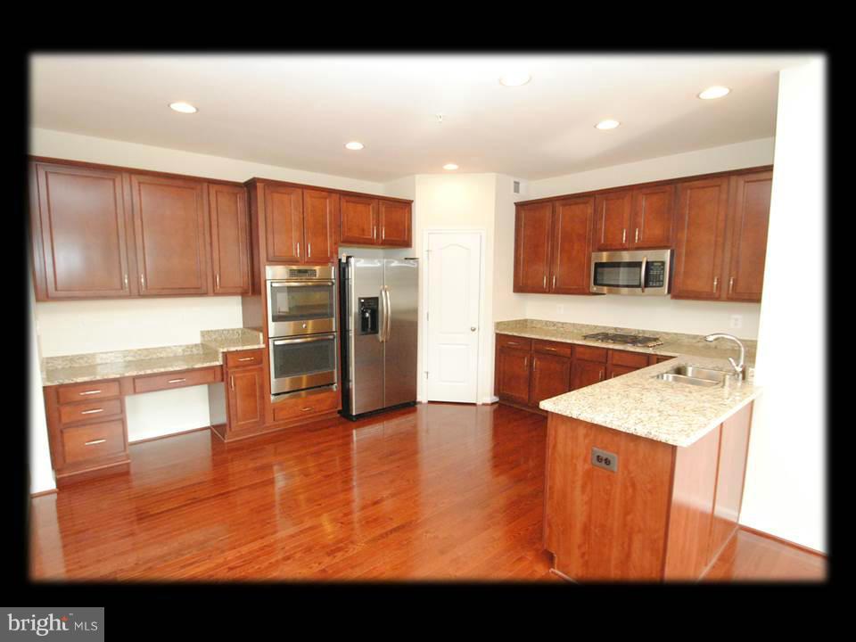 813 Wampler Road Baltimore, MD 21220 - Photo 12 of 30 a kitchen with stainless steel appliances granite countertop a refrigerator a stove and a sink with wooden floor