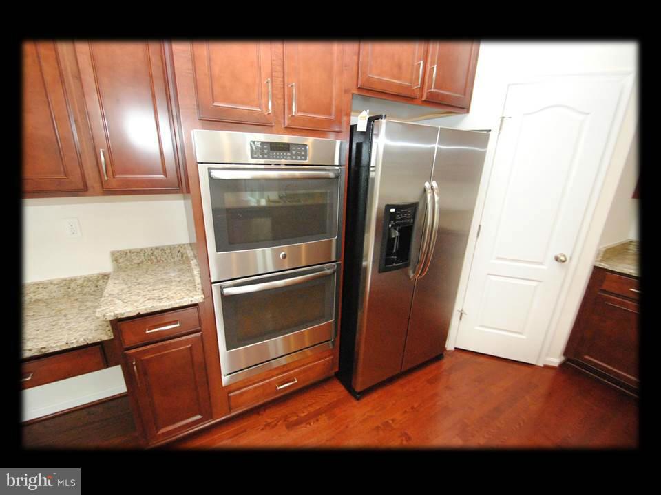 813 Wampler Road Baltimore, MD 21220 - Photo 14 of 30 a view of a refrigerator in kitchen and an empty room with wooden floor