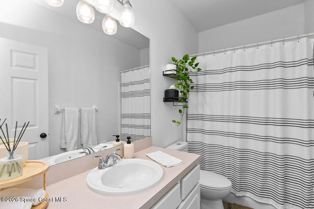 1209 Bolle Circle Rockledge, FL 32955 - Photo 19 of 28 a bathroom with a sink a toilet and mirror