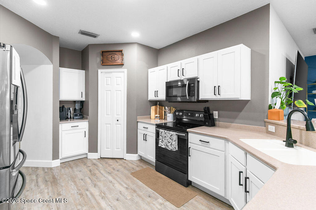 1209 Bolle Circle Rockledge, FL 32955 - Photo 3 of 28 a kitchen with a sink a refrigerator a stove top oven and white cabinets
