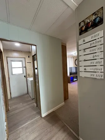 a view of a hallway to a livingroom with wooden floor and staircase