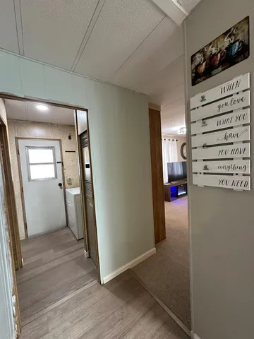 a view of a hallway to a livingroom with wooden floor and staircase