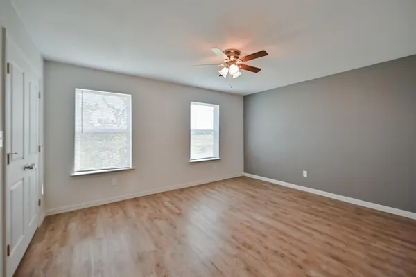 a view of an empty room with a window and wooden floor
