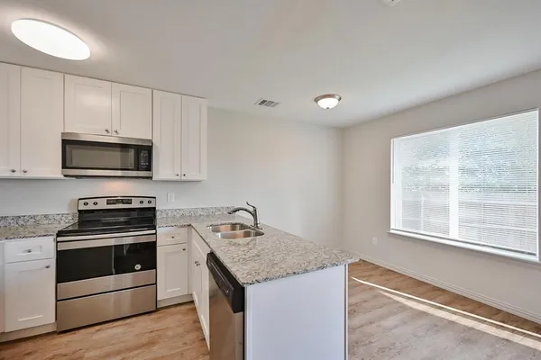 a kitchen with stainless steel appliances granite countertop a stove a microwave and a refrigerator