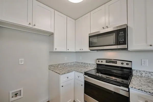 a kitchen with stainless steel appliances granite countertop white cabinets and a stove top oven