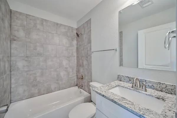 a bathroom with a granite countertop tub sink toilet and mirror