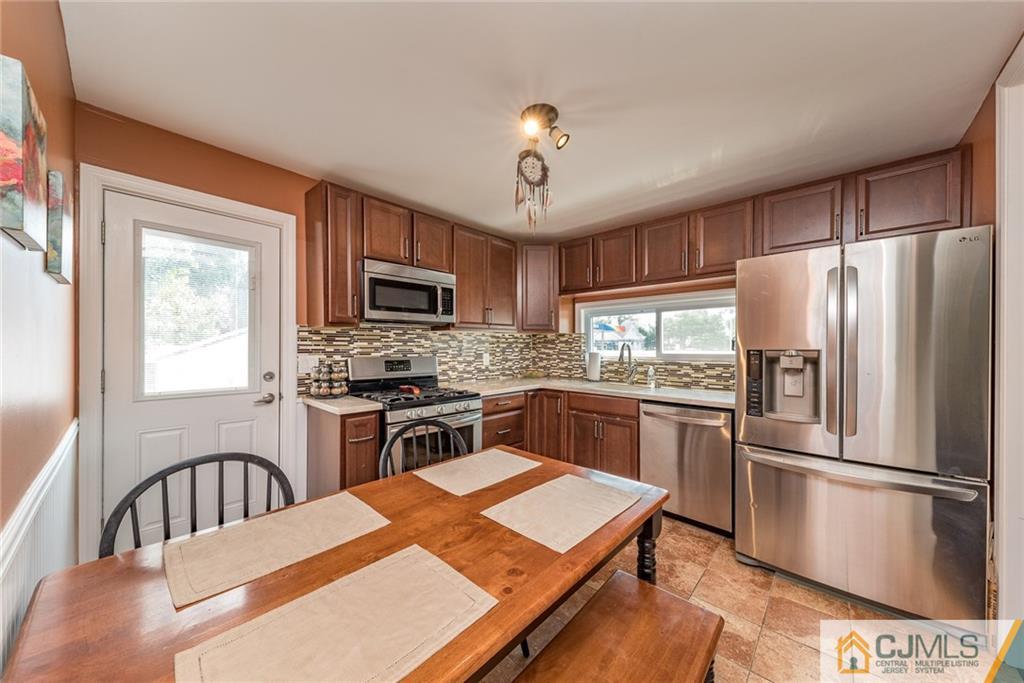 114 Dock Road Brick, NJ 08723 - Photo 9 of 25 a kitchen with stainless steel appliances granite countertop a refrigerator a stove top oven a sink dishwasher a dining table and chairs with wooden floor