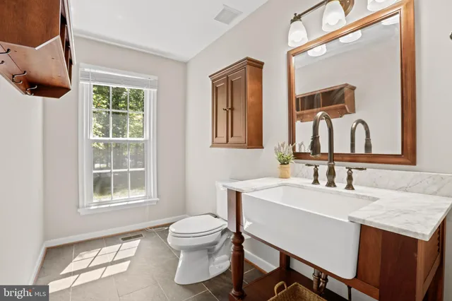 a bathroom with a sink a mirror a toilet and a window