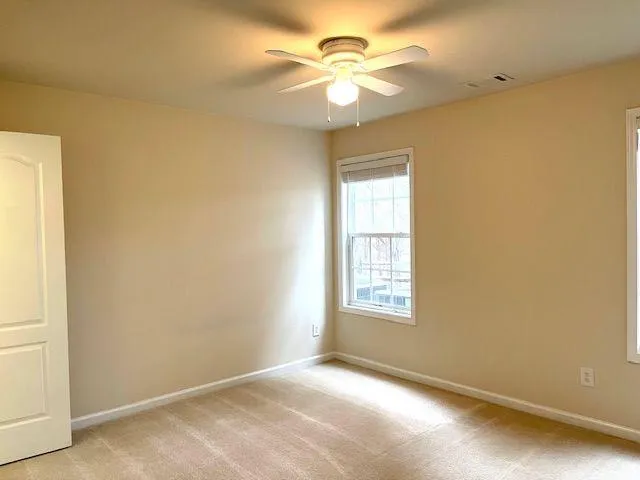 an empty room with windows and fan