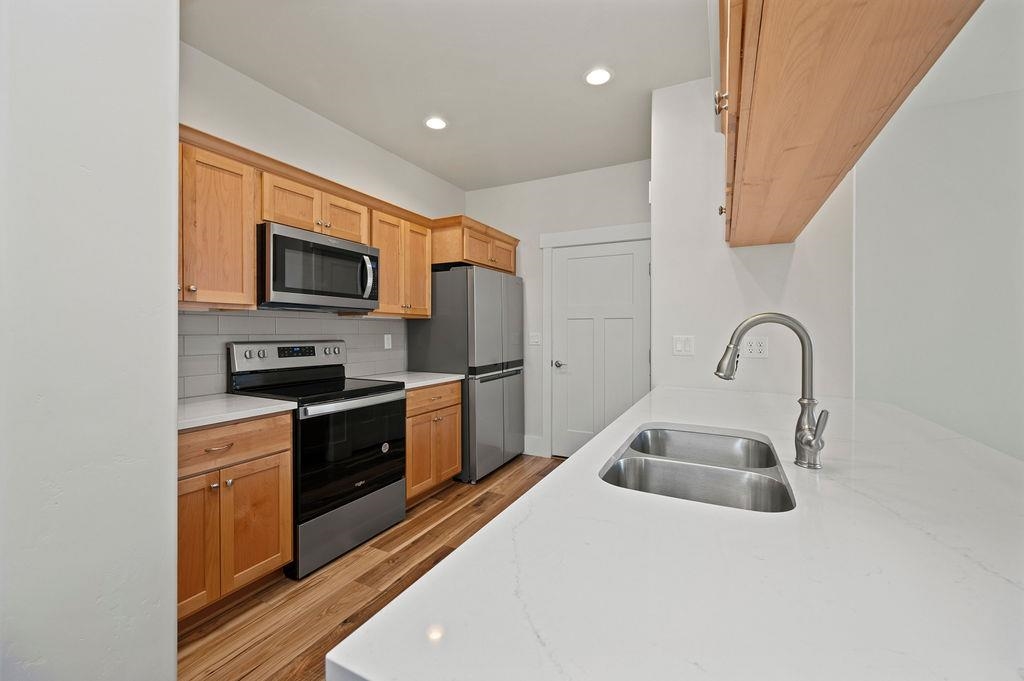 1243 Periwinkle Street Fruita, CO 81521 - Photo 13 of 24 a kitchen with stainless steel appliances granite countertop a sink a stove top oven a refrigerator with granite countertops and cabinets