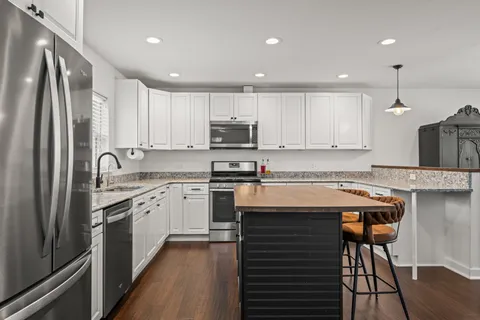 a kitchen with a stove a sink dishwasher a refrigerator and white cabinets with wooden floor