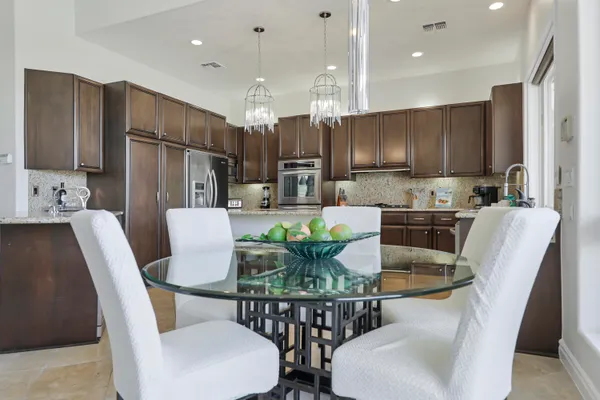 a kitchen with kitchen island a dining table chairs stainless steel appliances and cabinets