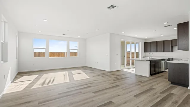 a view of an empty room with kitchen and window