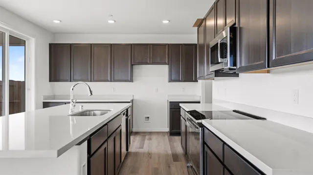 a kitchen with a sink dishwasher a stove and a refrigerator with wooden floor