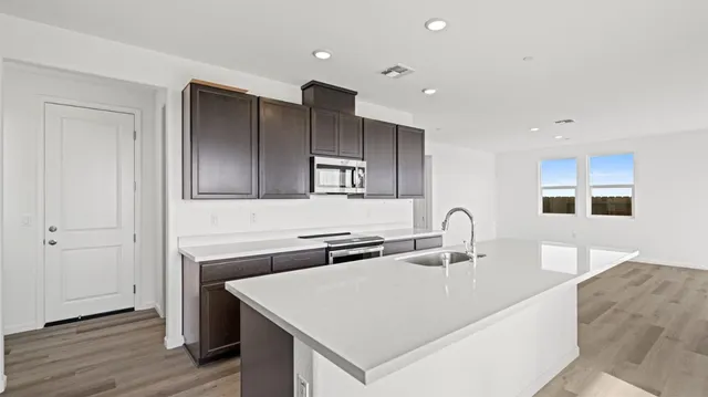 a kitchen with a sink a microwave and wooden floor