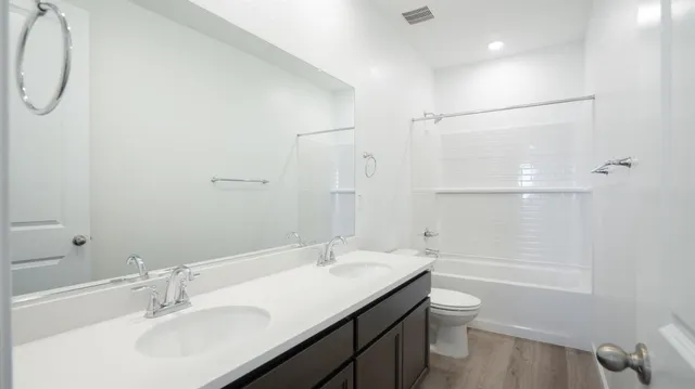a bathroom with a granite countertop sink a toilet and shower