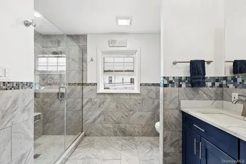 a bathroom with a granite countertop sink a mirror and shower