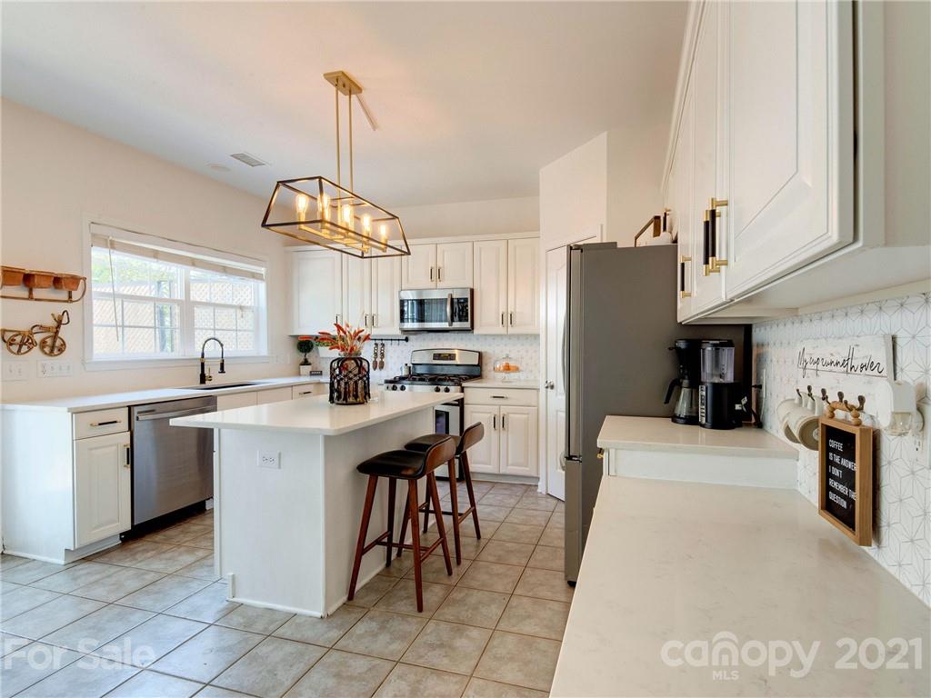 2405 Coltsgate Road Waxhaw, NC 28173 - Photo 21 of 48 a kitchen with stainless steel appliances granite countertop a refrigerator a sink dishwasher a dining table and chairs with wooden floor