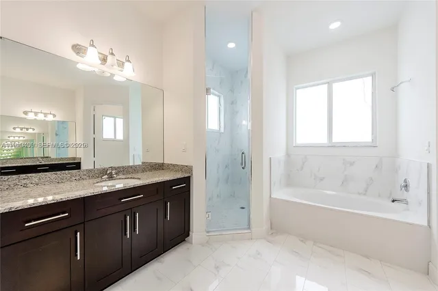 a bathroom with a granite countertop sink a large mirror and a bathtub